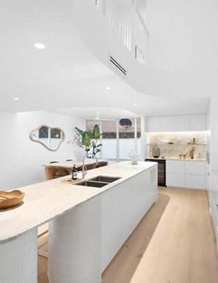Modern white kitchen with island and minimalist design in a property listing.
